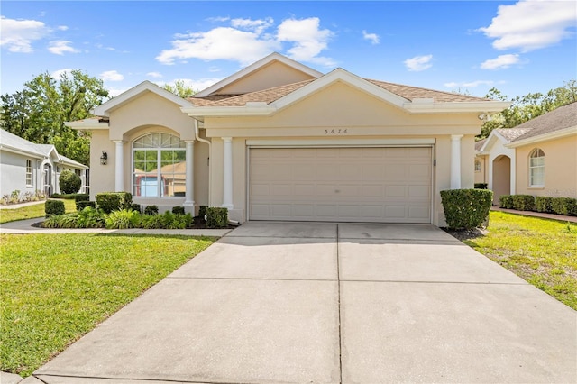 ranch-style house with a garage, driveway, stucco siding, and a front lawn