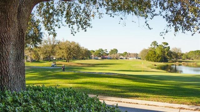 view of property's community with a lawn, a water view, and view of golf course