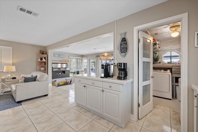 4400 Floramar Ter, New Port Richey, FL 34652 - kitchen with washer / clothes dryer, white cabinetry, visible vents, open floor plan, and tile counters