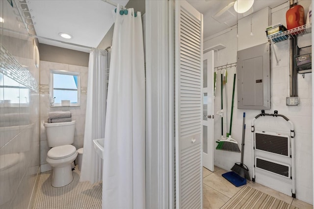 4400 Floramar Ter, New Port Richey, FL 34652 - bathroom featuring electric panel, tile patterned floors, toilet, ceiling fan, and tile walls