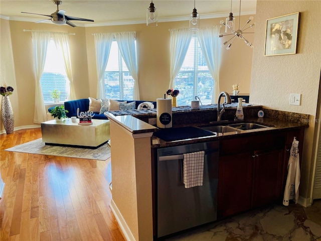 kitchen with a sink, stainless steel dishwasher, dark countertops, and light wood-style flooring