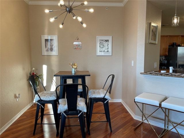 dining room with dark wood-type flooring, a notable chandelier, baseboards, and crown molding