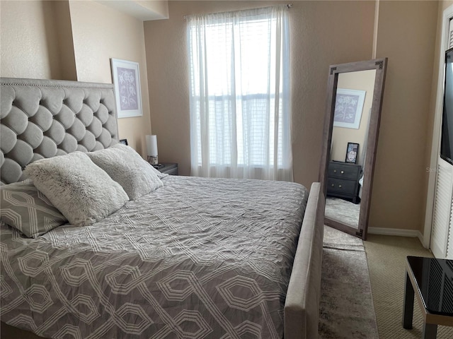 carpeted bedroom with baseboards and multiple windows