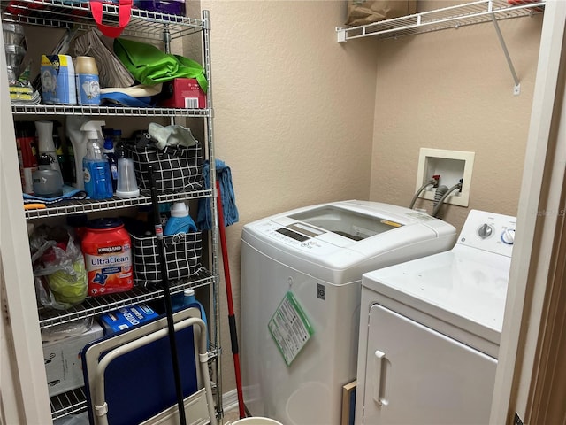 washroom with a textured wall, washer and clothes dryer, and laundry area