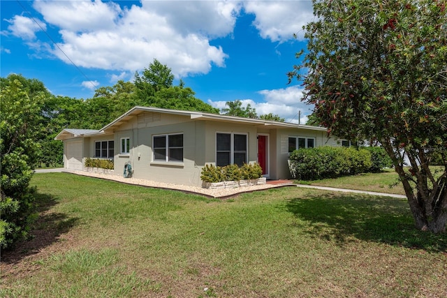 rear view of property featuring an attached garage, concrete block siding, and a lawn