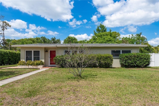 ranch-style house featuring fence and a front lawn