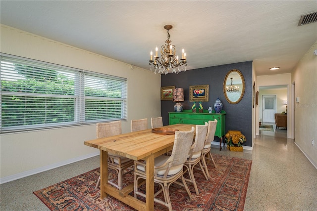 dining area featuring a chandelier, visible vents, baseboards, and speckled floor