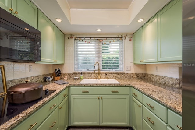 kitchen with green cabinets, a sink, a raised ceiling, decorative backsplash, and black appliances