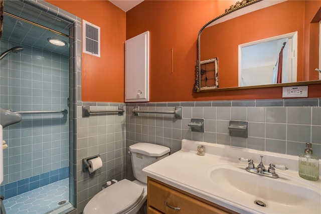 bathroom featuring a shower stall, vanity, visible vents, a wainscoted wall, and toilet