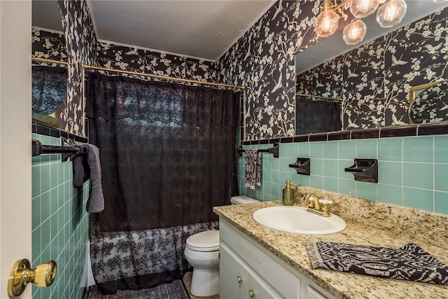 full bath with vanity, wallpapered walls, curtained shower, a wainscoted wall, and tile walls