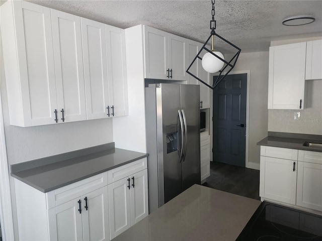 825 Lincoln Ave, Tarpon Springs, FL 34689 - kitchen with white cabinets, dark wood finished floors, dark countertops, stainless steel fridge, and a textured ceiling