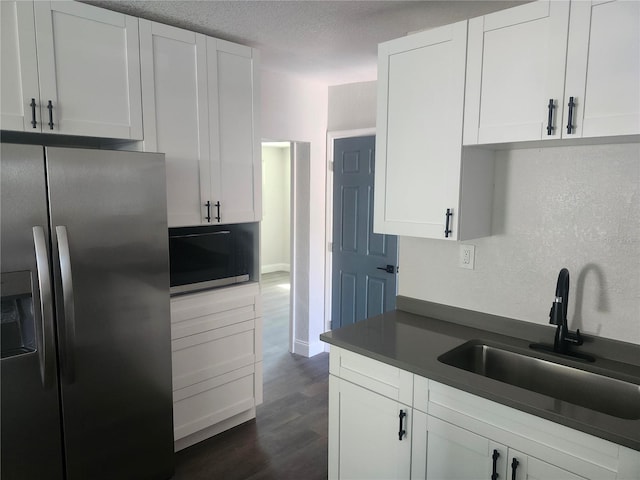 825 Lincoln Ave, Tarpon Springs, FL 34689 - kitchen with dark countertops, a sink, black microwave, stainless steel fridge with ice dispenser, and white cabinetry