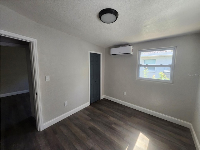 825 Lincoln Ave, Tarpon Springs, FL 34689 - unfurnished bedroom with dark wood finished floors, an AC wall unit, baseboards, and a textured ceiling
