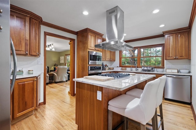 kitchen featuring light wood-style flooring, crown molding, appliances with stainless steel finishes, and island range hood