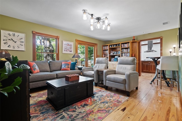 living room with visible vents, light wood finished floors, and a chandelier