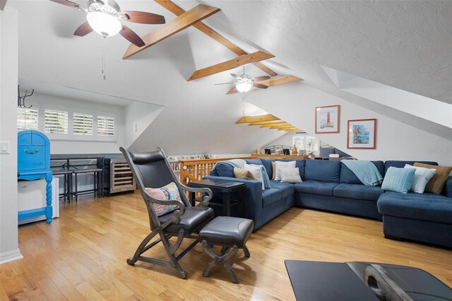 living area with a textured ceiling, a ceiling fan, beverage cooler, vaulted ceiling with beams, and wood finished floors