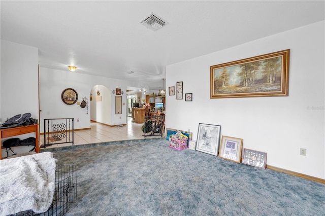 carpeted living area with arched walkways, visible vents, and tile patterned flooring