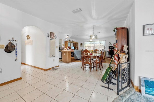 dining room featuring baseboards, arched walkways, and light tile patterned flooring