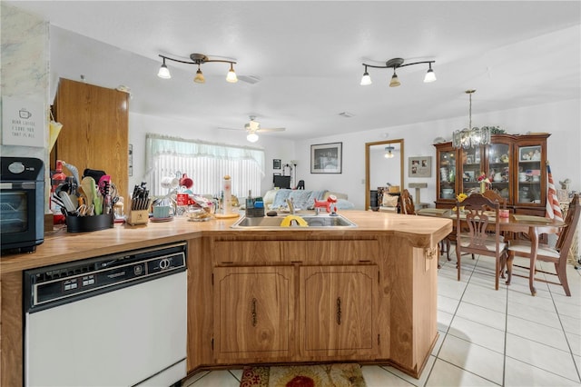 kitchen featuring a sink, light tile patterned floors, white dishwasher, and a peninsula
