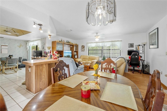 dining space featuring light tile patterned floors, baseboards, and ceiling fan with notable chandelier