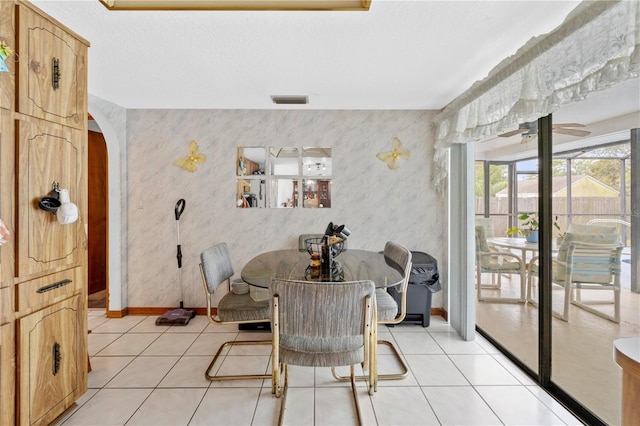 dining room with visible vents, baseboards, arched walkways, wallpapered walls, and light tile patterned flooring