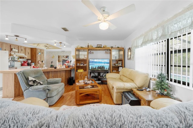 living area featuring wood finished floors, ceiling fan, and visible vents