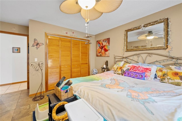 tiled bedroom with a closet, baseboards, and a ceiling fan