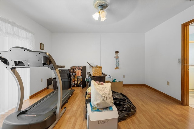 workout room featuring light wood finished floors, baseboards, and a ceiling fan