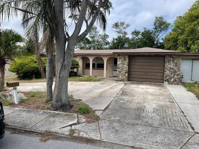 11515 Meredith Ln, Port Richey, FL 34668 - view of front facade featuring a garage, stone siding, driveway, and stucco siding