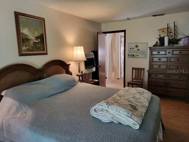 bedroom with a textured ceiling, carpet flooring, and visible vents