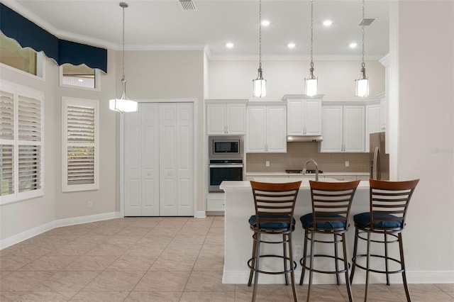 877 N Hunt Club Dr, Hernando, FL 34442 - kitchen with under cabinet range hood, a kitchen bar, ornamental molding, and appliances with stainless steel finishes