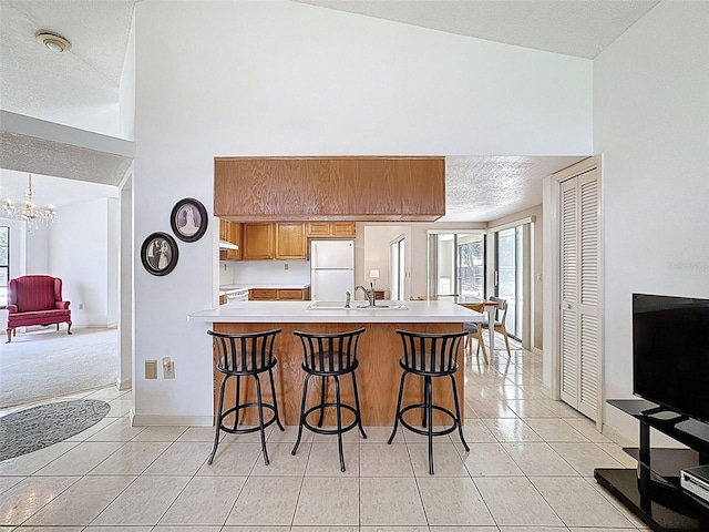 kitchen with light tile patterned flooring, freestanding refrigerator, light countertops, and a sink
