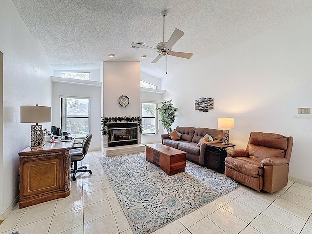 living area with a textured ceiling, a ceiling fan, a tile fireplace, high vaulted ceiling, and light tile patterned floors