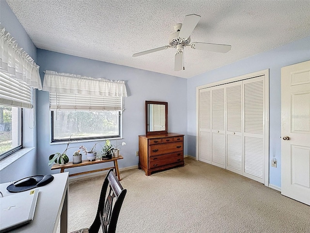 office featuring baseboards, a textured ceiling, light colored carpet, and ceiling fan