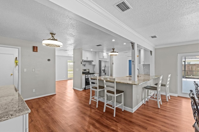 155 Patty Ann Blvd, Palm Harbor, FL 34683 - kitchen with visible vents, appliances with stainless steel finishes, a breakfast bar area, and under cabinet range hood