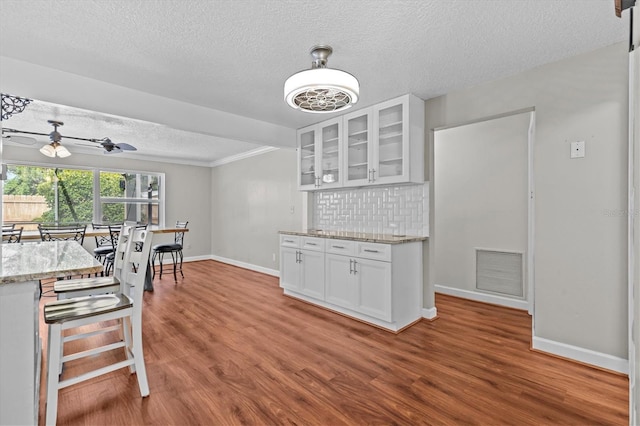 155 Patty Ann Blvd, Palm Harbor, FL 34683 - kitchen with white cabinetry, wood finished floors, backsplash, and visible vents