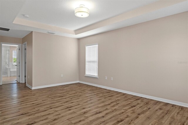 13619 Hunters Point St, Spring Hill, FL 34609 - spare room with a raised ceiling, visible vents, baseboards, and wood finished floors