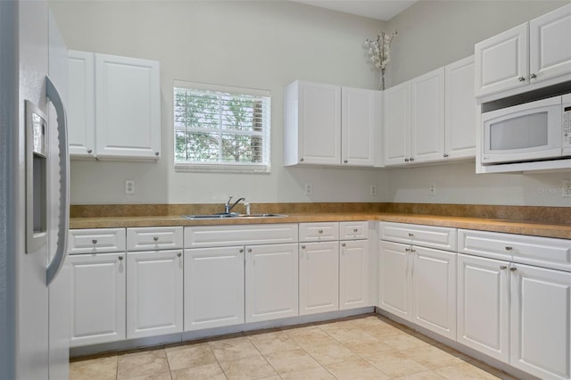 13619 Hunters Point St, Spring Hill, FL 34609 - kitchen with white microwave, light tile patterned floors, refrigerator with ice dispenser, white cabinets, and a sink