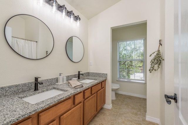 full bathroom featuring toilet, double vanity, lofted ceiling, baseboards, and tile patterned flooring