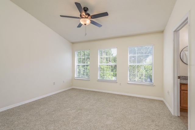 unfurnished room with light colored carpet, ceiling fan, baseboards, and vaulted ceiling