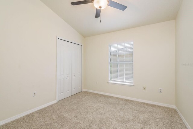 unfurnished bedroom featuring carpet flooring, baseboards, vaulted ceiling, and a closet