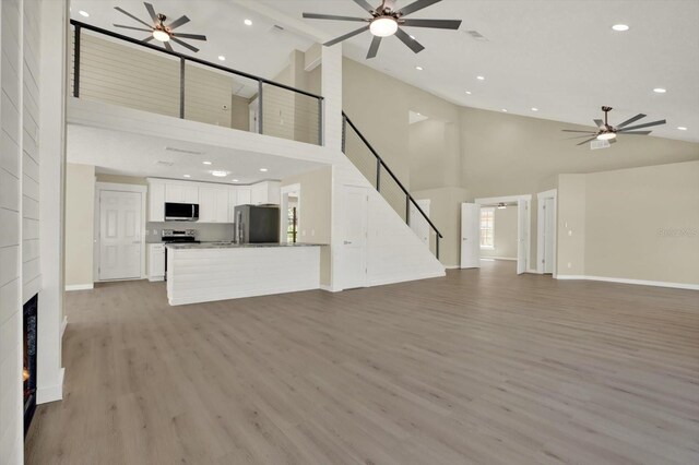 10423 Ashley Oaks Dr, Riverview, FL 33578 - unfurnished living room with light wood finished floors, recessed lighting, stairway, ceiling fan, and high vaulted ceiling