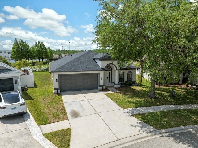 single story home with stucco siding, roof with shingles, a front yard, an attached garage, and concrete driveway