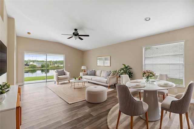 living room featuring ceiling fan, vaulted ceiling, recessed lighting, a water view, and wood finished floors