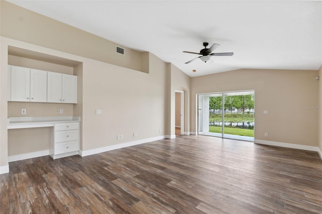 unfurnished living room with built in desk, vaulted ceiling, dark wood finished floors, visible vents, and ceiling fan