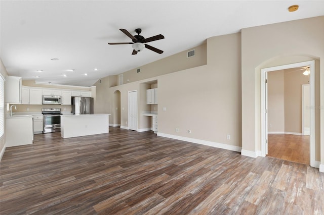 unfurnished living room with visible vents, dark wood-style flooring, a sink, ceiling fan, and vaulted ceiling
