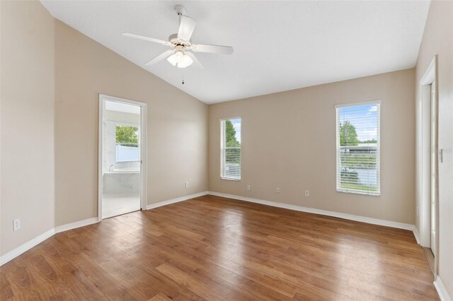 spare room featuring light wood-style flooring, ceiling fan, vaulted ceiling, and baseboards