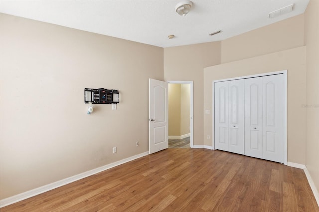 unfurnished bedroom featuring a closet, visible vents, light wood-type flooring, and baseboards
