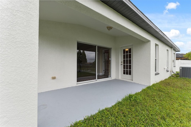 rear view of house with a yard, central air condition unit, a patio, and stucco siding
