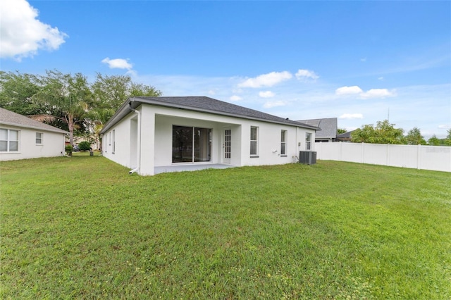 back of house featuring central AC, fence, a lawn, and stucco siding